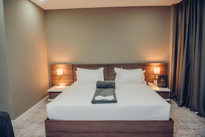 Une chambre avec un grand lit recouvert d'une couette blanche et de coussins.