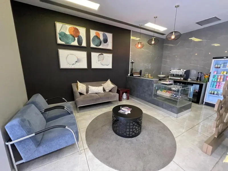 Un espace d'attente moderne avec des fauteuils, un canapé et un comptoir de boissons.