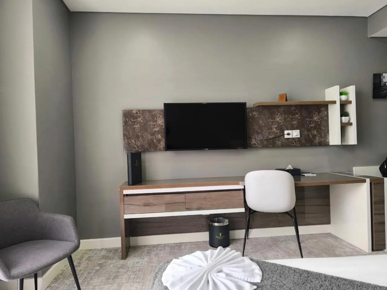 Un espace de travail avec un bureau, une chaise et un téléviseur mural.
