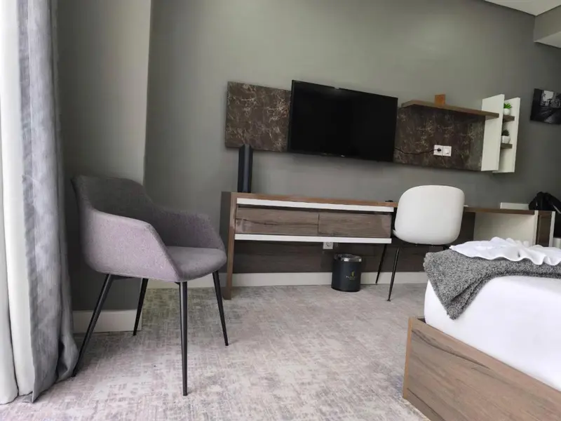 Une chambre moderne avec un téléviseur mural et des fauteuils.