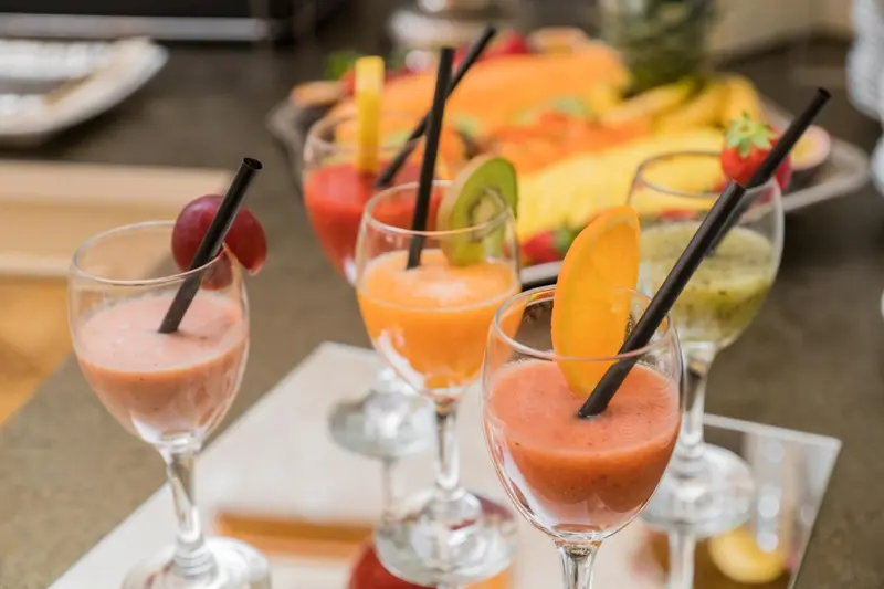 Des boissons colorées et des fruits frais sont présentés sur un comptoir.