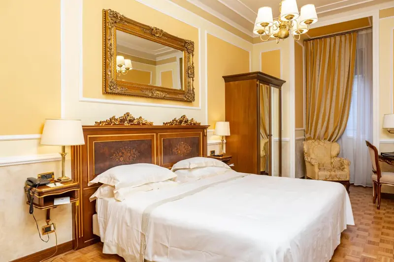 Une chambre à coucher lumineuse avec un grand lit et un miroir doré.