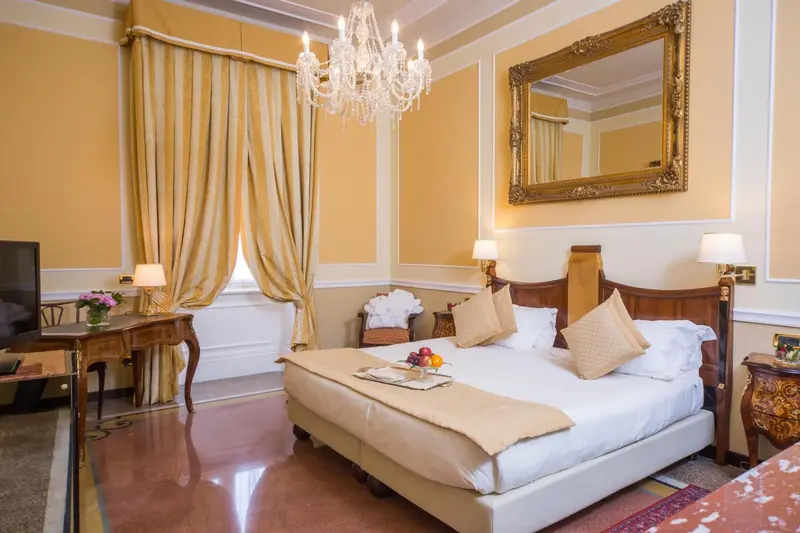 Une chambre lumineuse avec un grand lit et un miroir doré.