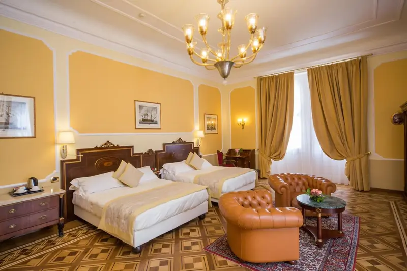 Chambre lumineuse avec deux lits et un fauteuil en cuir.