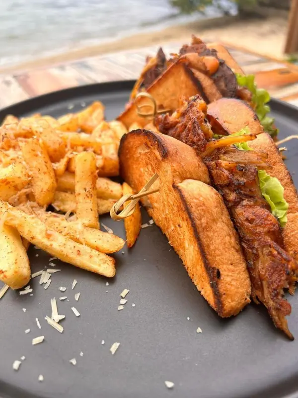 Assiette généreuse de sandwich et de frites servies sur une table sombre.