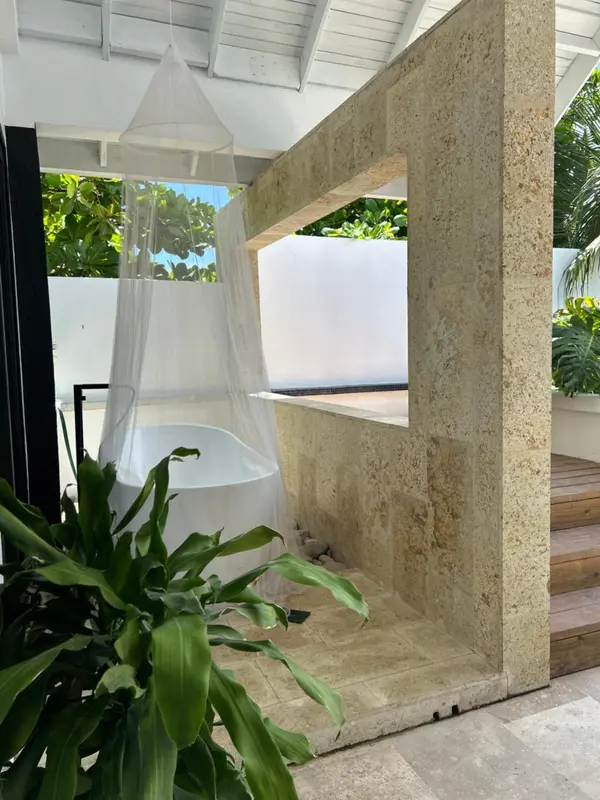 Baignoire blanche dans une salle de bain extérieure en pierre claire.
