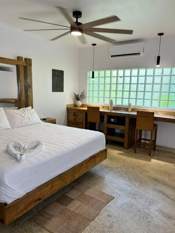Une chambre lumineuse avec un grand lit et un espace bureau.