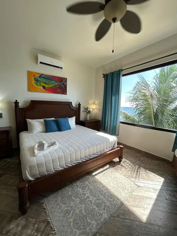 Une chambre lumineuse avec un grand lit et une vue sur la végétation.