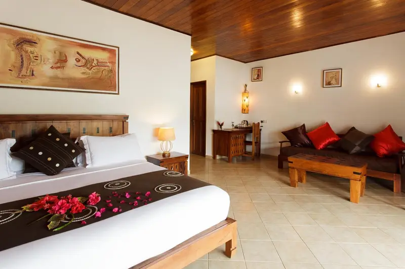 Une chambre lumineuse avec un grand lit et un coin salon.
