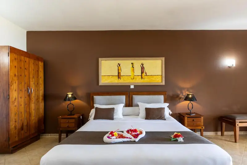 Une chambre avec un grand lit recouvert d'une courtepointe blanche et de fleurs.