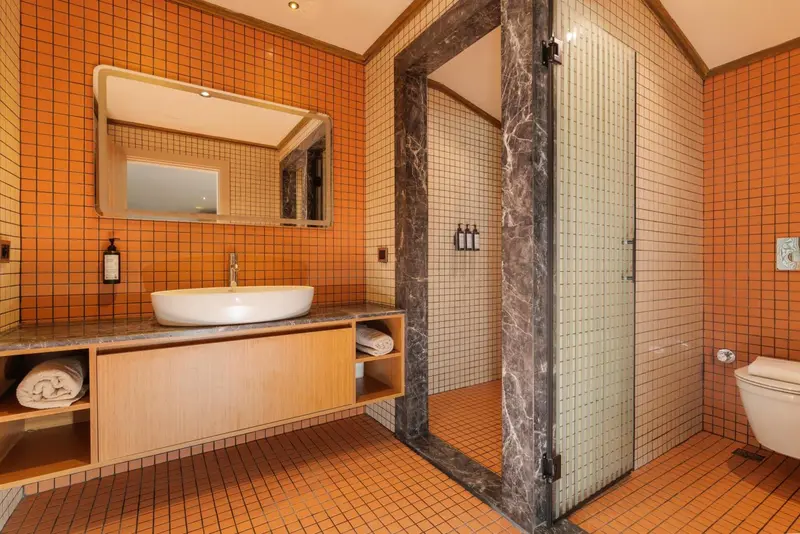 Une salle de bain moderne avec douche à l'italienne et carrelage orange.