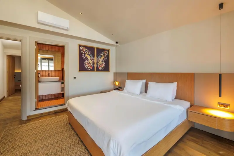 Chambre lumineuse avec un grand lit et une décoration murale colorée.