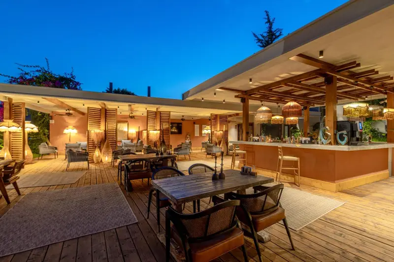 Terrasse de restaurant avec tables et comptoir de bar en soirée.