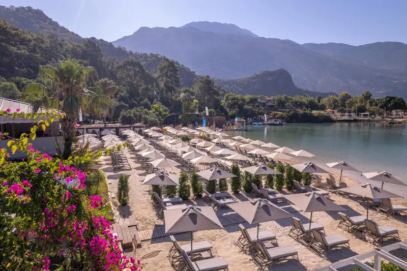 Plage de sable avec transats et parasols face à une baie abritée.