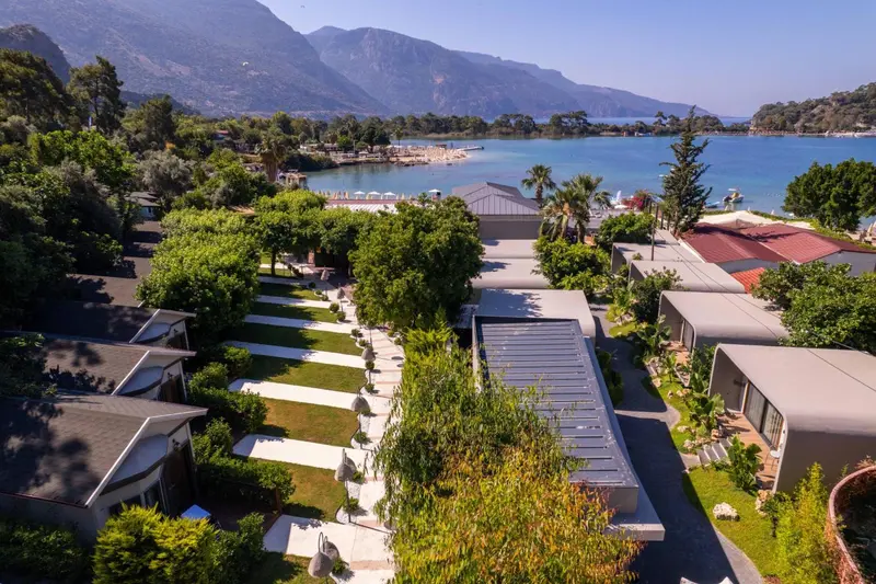 Vue aérienne d'un complexe hôtelier avec des bâtiments bas et une végétation luxuriante au bord de la mer.