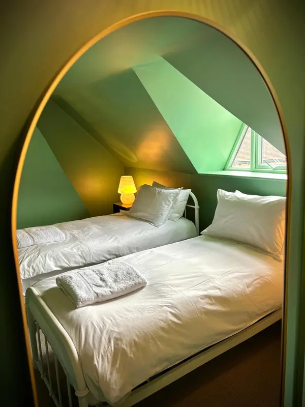 Une chambre mansardée avec deux lits simples et une décoration sobre.