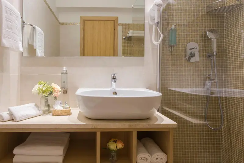 Une salle de bain lumineuse avec une douche à l'italienne et un vasque sur un meuble.
