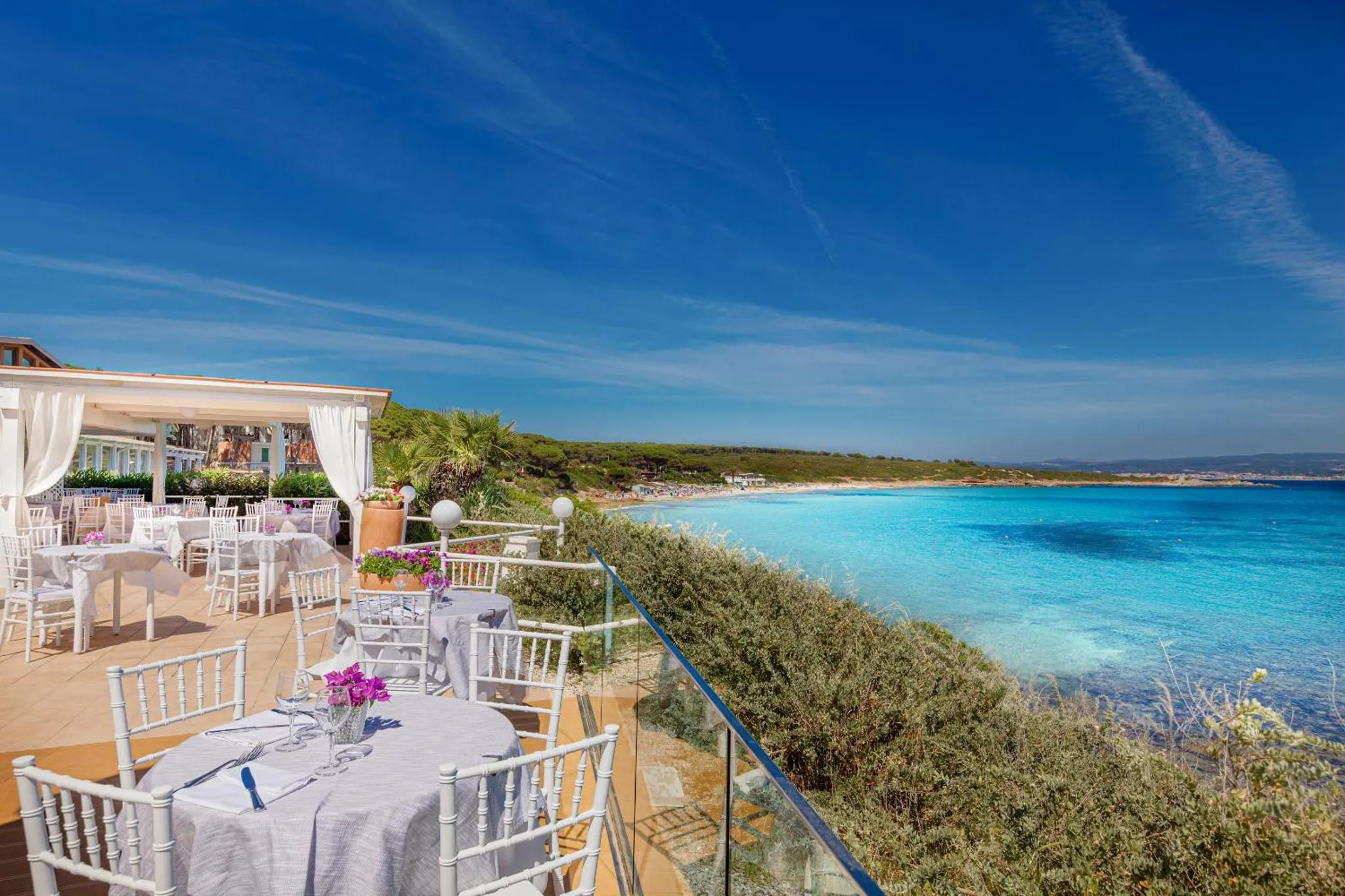 Terrasse ombragée avec tables dressées face à la mer.