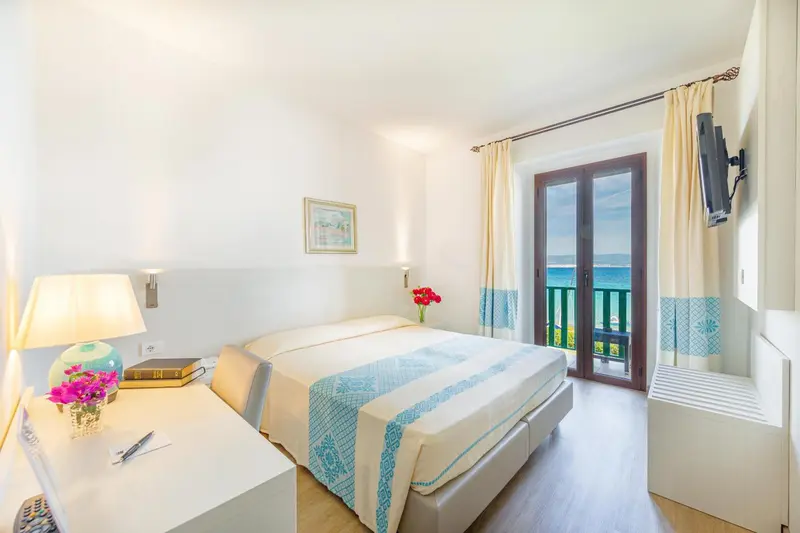 Une chambre lumineuse avec un lit double et une vue sur la mer.