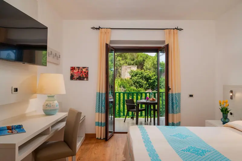 Une chambre lumineuse s'ouvre sur une terrasse avec vue sur la végétation.