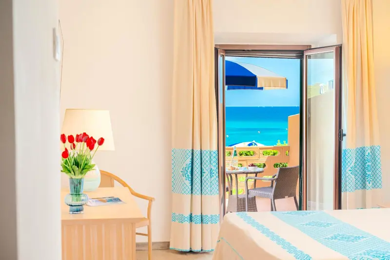 Une chambre lumineuse avec vue sur la mer depuis une terrasse.