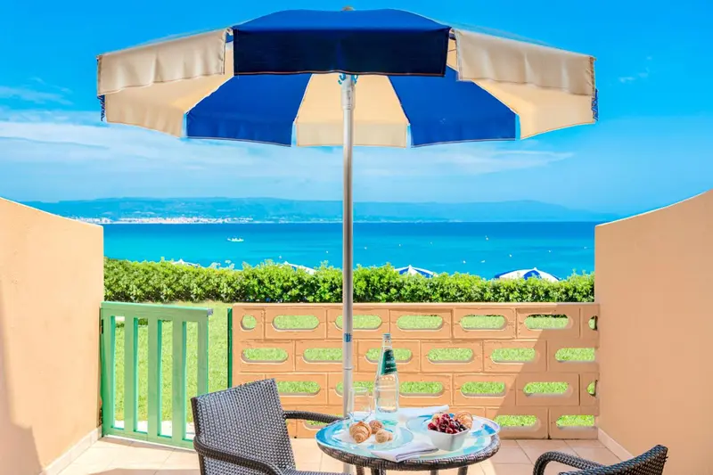 Une terrasse avec une table basse et des chaises offre une vue sur la mer.