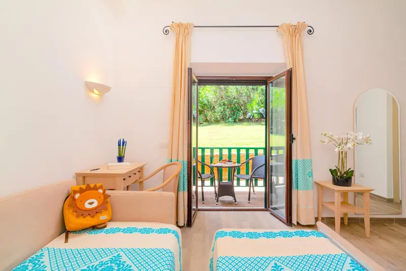 Une chambre lumineuse s'ouvre sur une terrasse avec table et chaises.