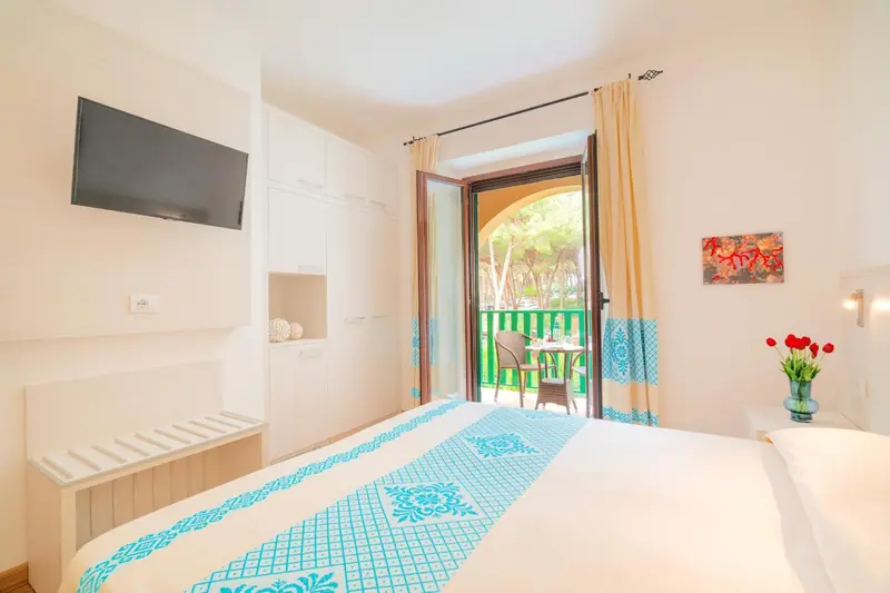 Une chambre lumineuse avec un lit recouvert d'une courtepointe décorative et un accès à une terrasse.