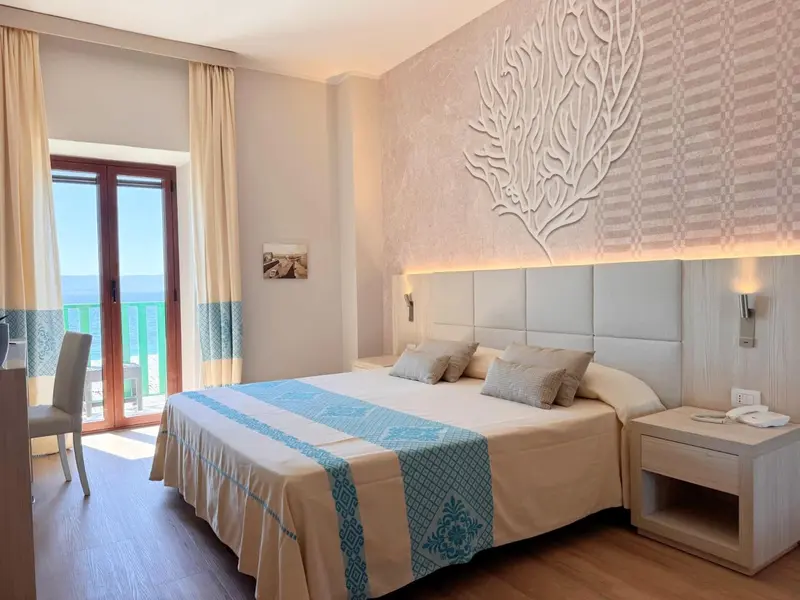 Chambre lumineuse avec un grand lit et vue sur la mer.