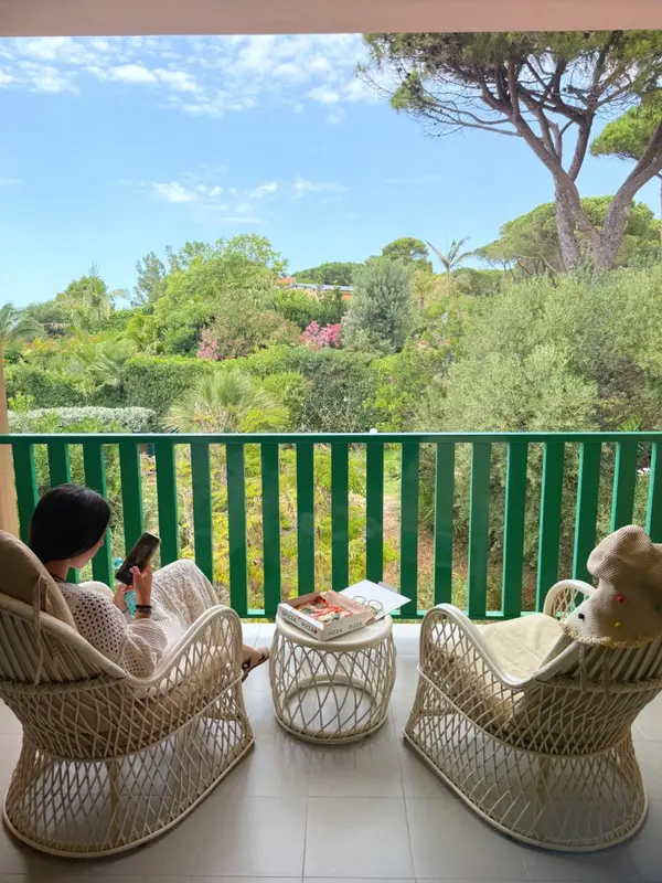Une terrasse avec deux fauteuils blancs et une petite table.