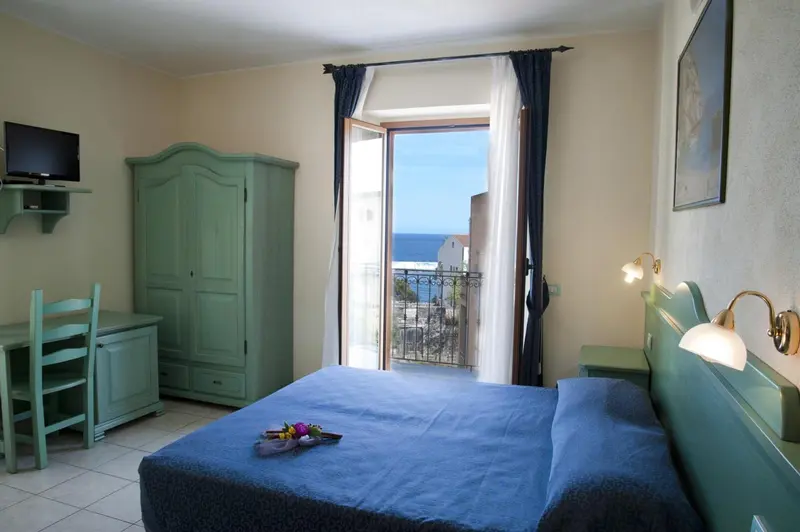 Une chambre lumineuse avec un lit fait et un accès à un balcon.