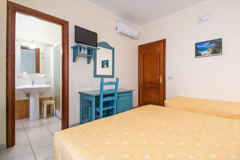 Une chambre lumineuse avec un lit et un coin lavabo.