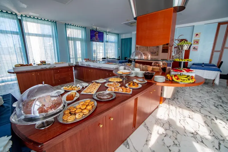 Un buffet propose une variété de pâtisseries et de fruits frais dans une salle lumineuse.
