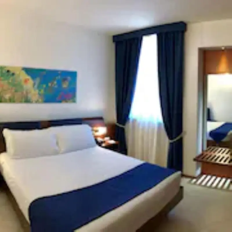Une chambre lumineuse avec un grand lit recouvert d'une courtepointe bleue.