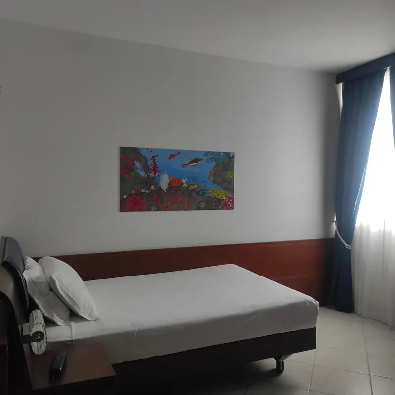 Une chambre lumineuse avec un lit simple et une décoration murale colorée.