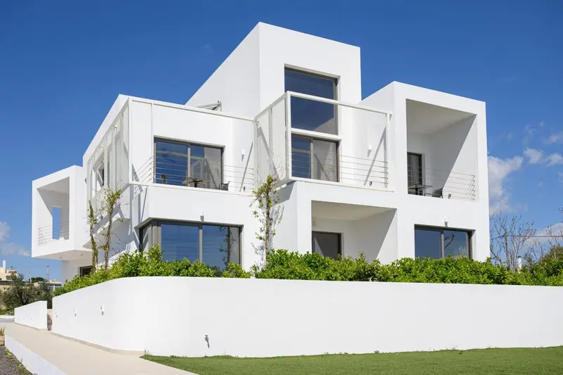 Architecture moderne blanche avec végétation luxuriante devant.