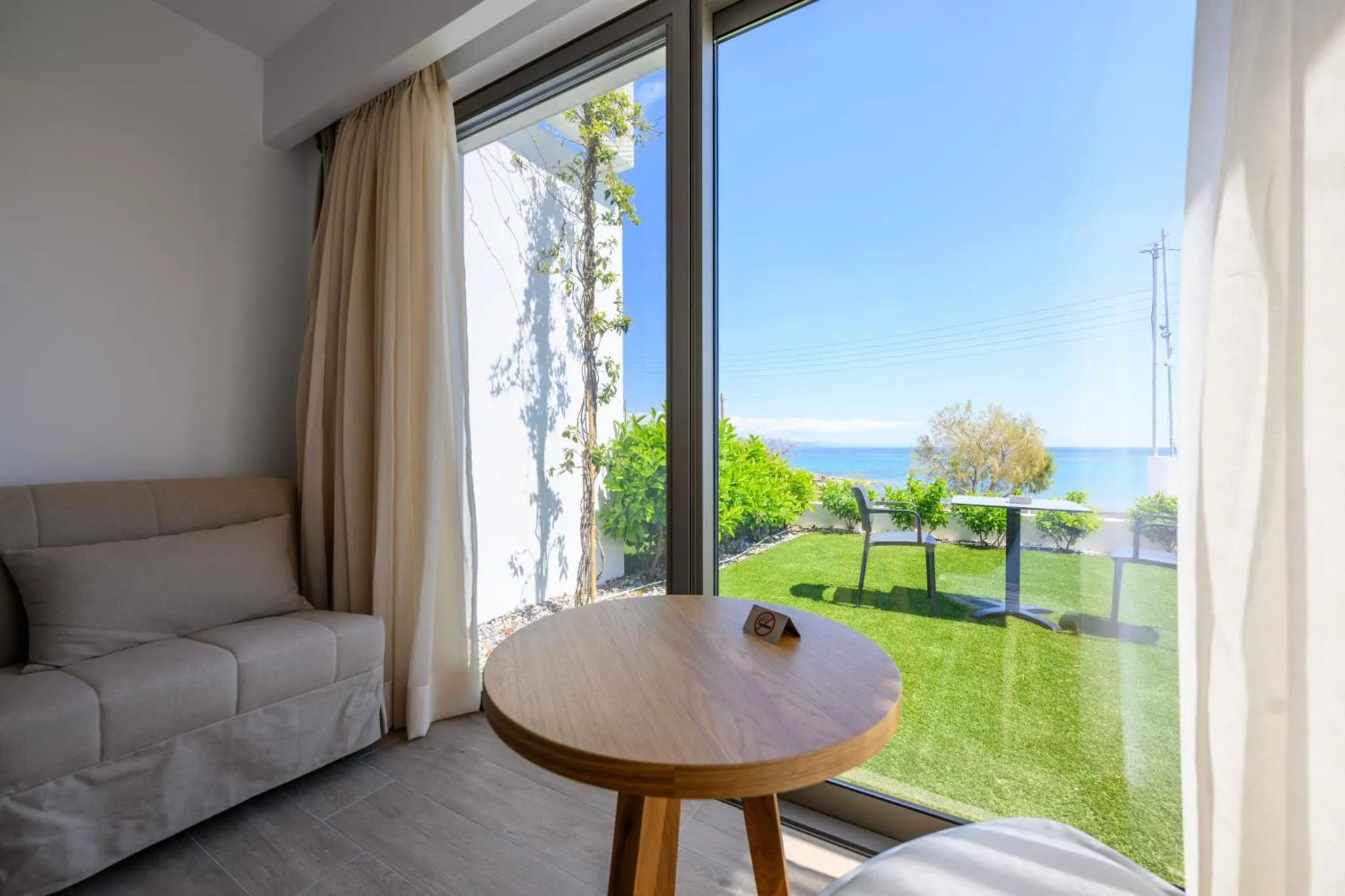 Une pièce lumineuse donne sur une terrasse et un jardin verdoyant avec vue sur la mer.