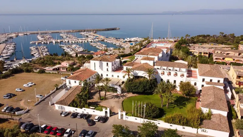 Vue aérienne d'un complexe hôtelier blanc avec piscine et marina à proximité.