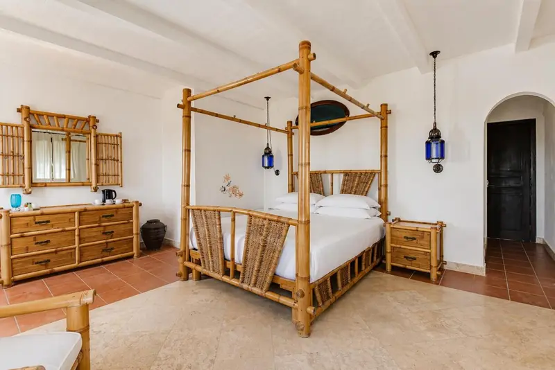 Une chambre lumineuse avec un grand lit à baldaquin en bambou.