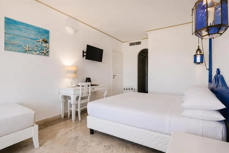 Chambre lumineuse avec un lit blanc et un bureau.