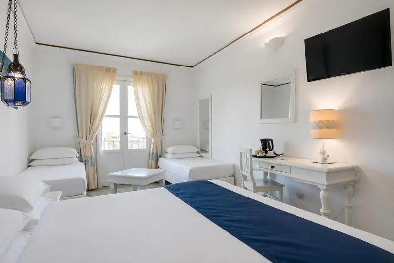 Une chambre lumineuse avec deux lits simples et un bureau blanc.