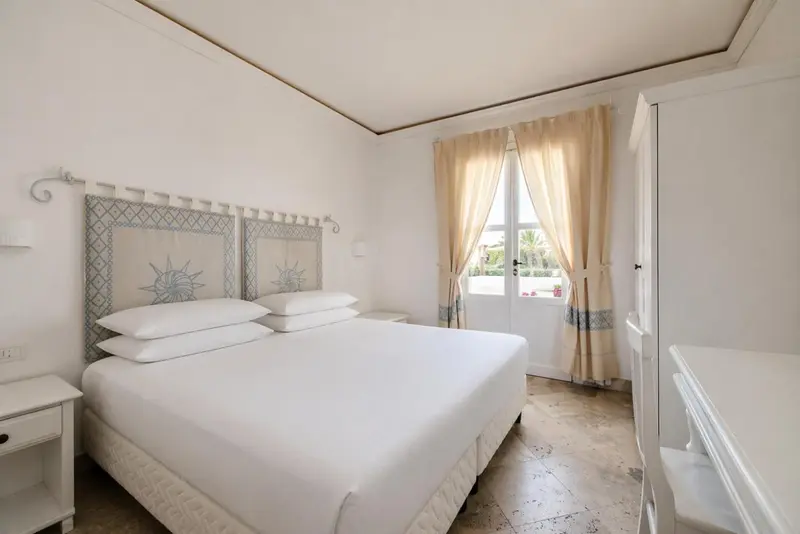 Une chambre lumineuse avec un lit double et une fenêtre.