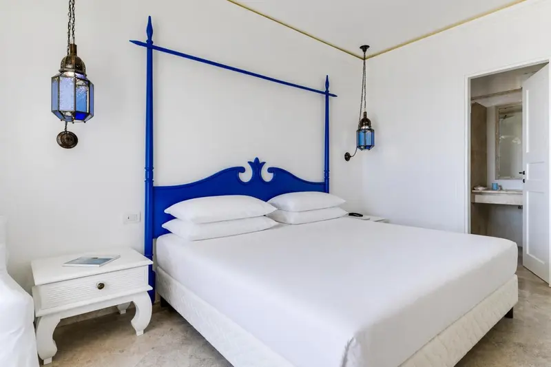 Une chambre lumineuse avec un grand lit à baldaquin bleu.