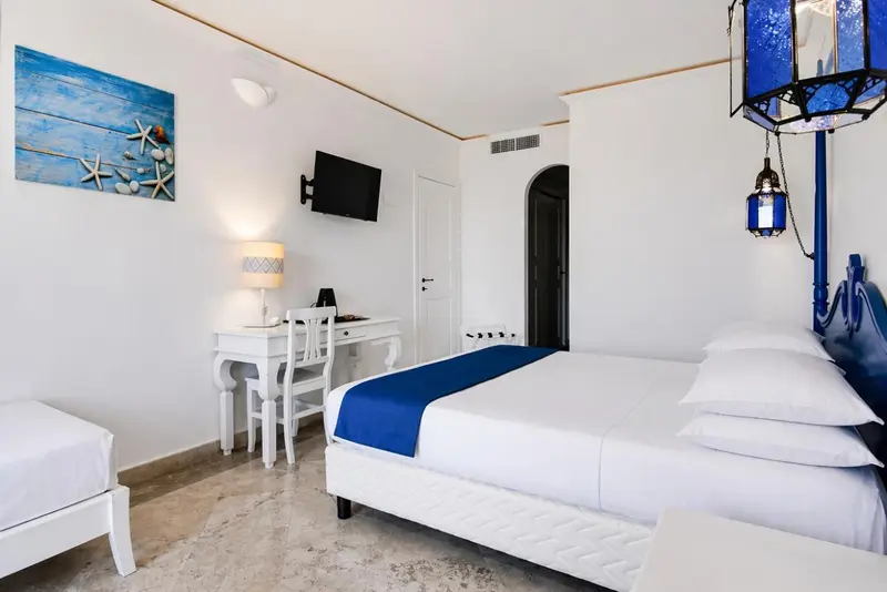 Une chambre lumineuse avec un lit fait et un bureau blanc.