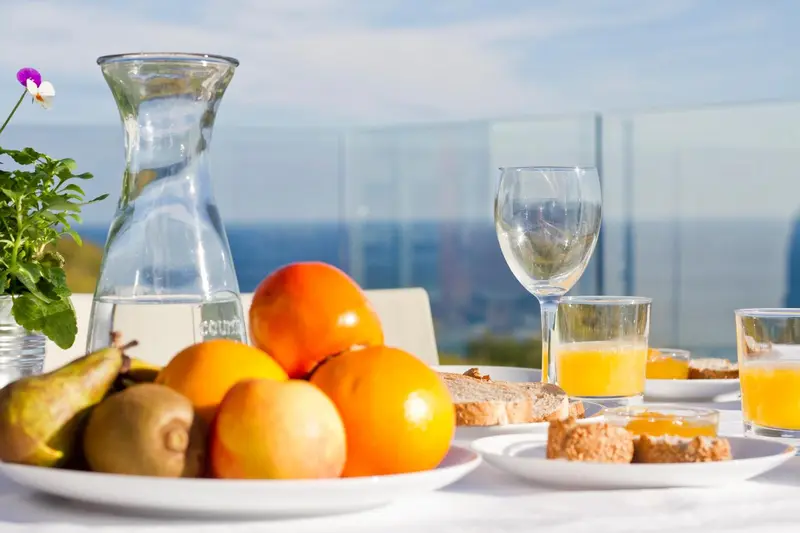 Une table est dressée avec des fruits frais, du pain et des jus.