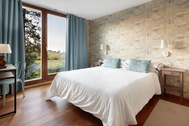 Une chambre lumineuse avec un grand lit et une vue sur la campagne.