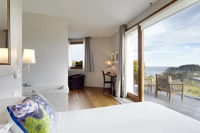 Une chambre lumineuse avec un grand balcon donnant sur la mer.