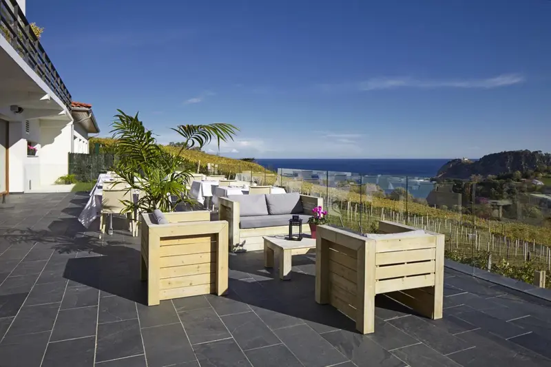 Terrasse aménagée avec mobilier en bois et vue sur la mer.