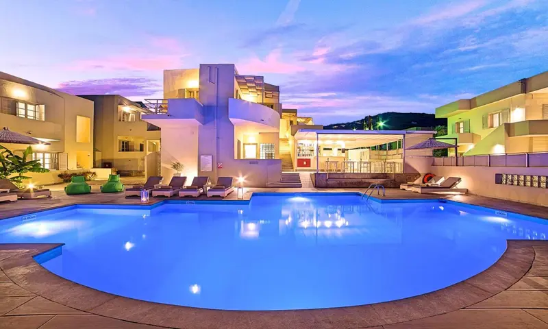 Piscine d'hôtel illuminée au crépuscule avec des transats et une architecture moderne.
