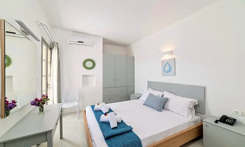 Une chambre lumineuse avec un lit fait et une coiffeuse.